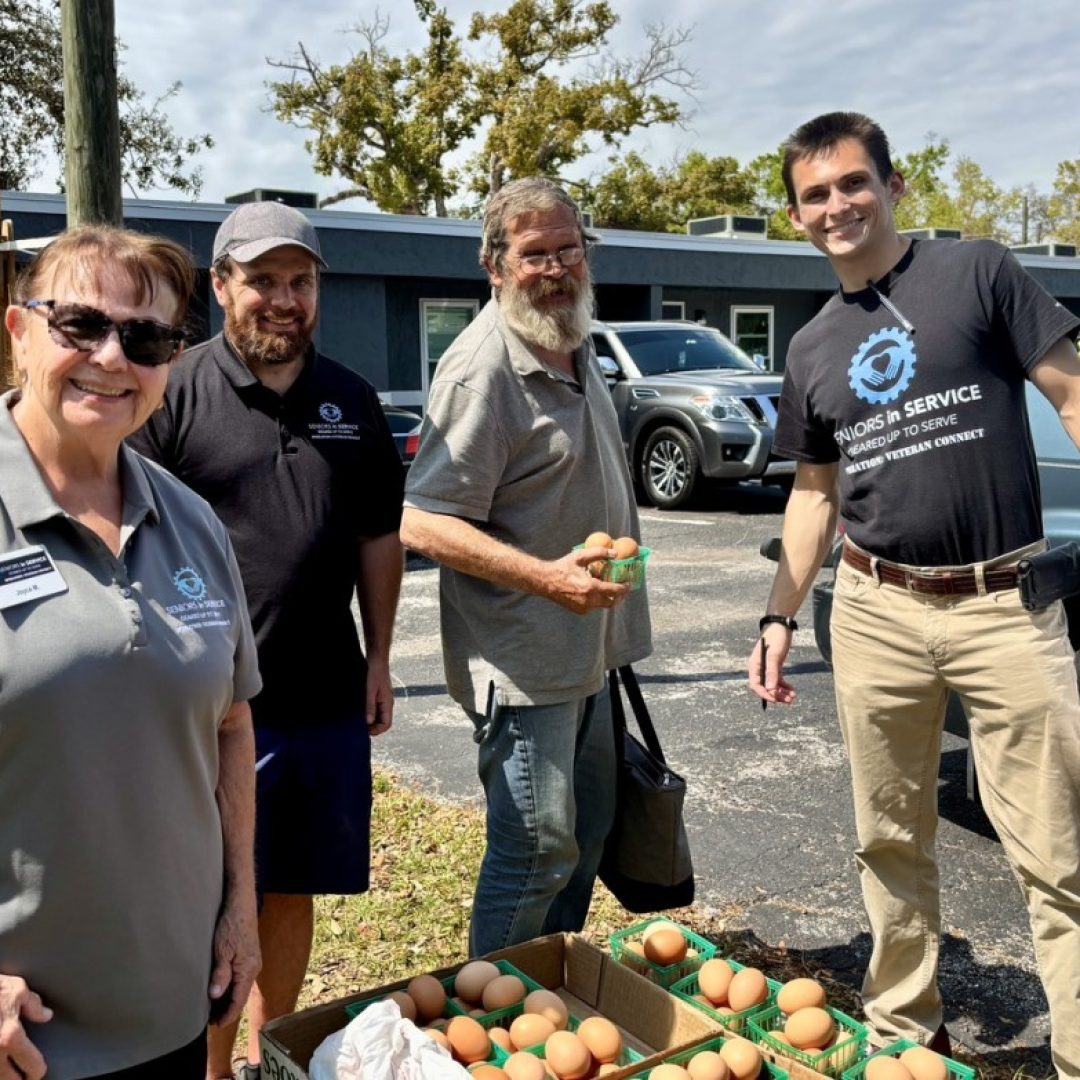Veteran receives fresh eggs at community event with Seniors in Service Operation: Veteran Connect members and staff.