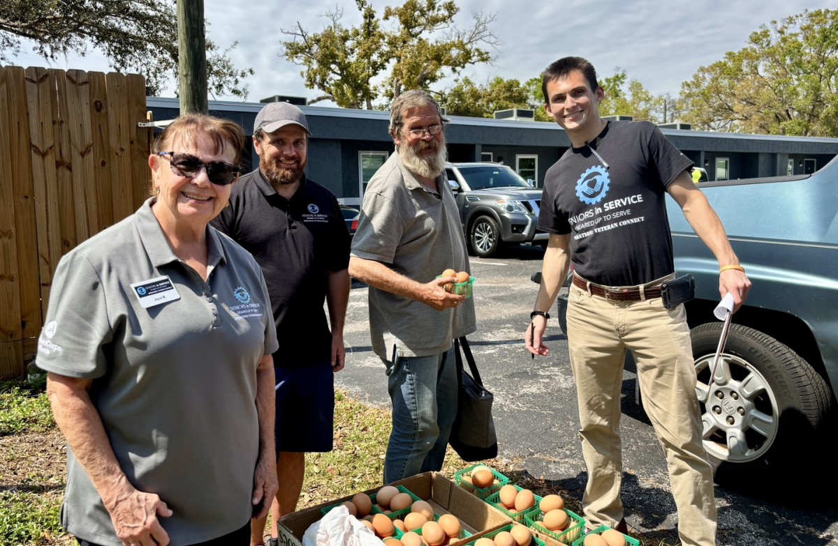 Veteran receives fresh eggs at community event with Seniors in Service Operation: Veteran Connect members and staff.
